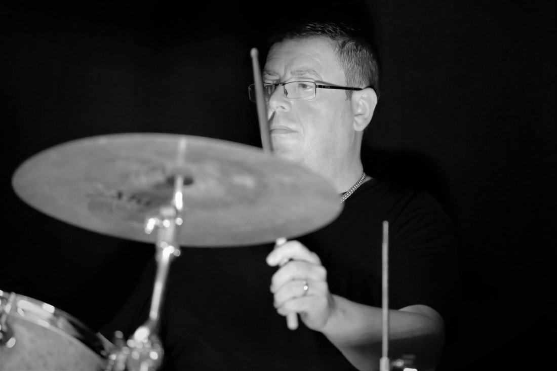 Mark McLaughlan on drums in black and white playing celtic fusion music